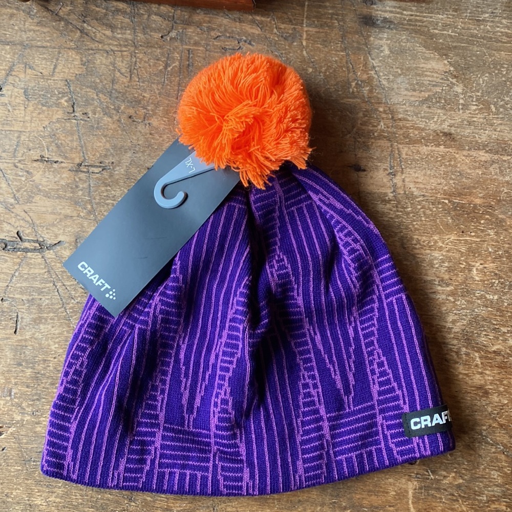 Knit hat by CRAFT in purple deco print with orange Pom Pom. Never worn. L/XL.